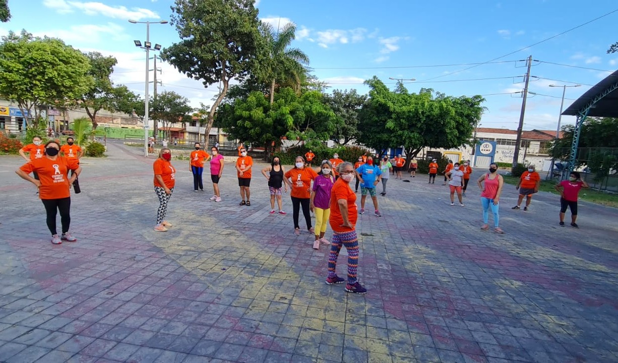 grupo de senhoras numa praça com roupas de ginástica, máscara e mantendo o distanciamento de dois metros